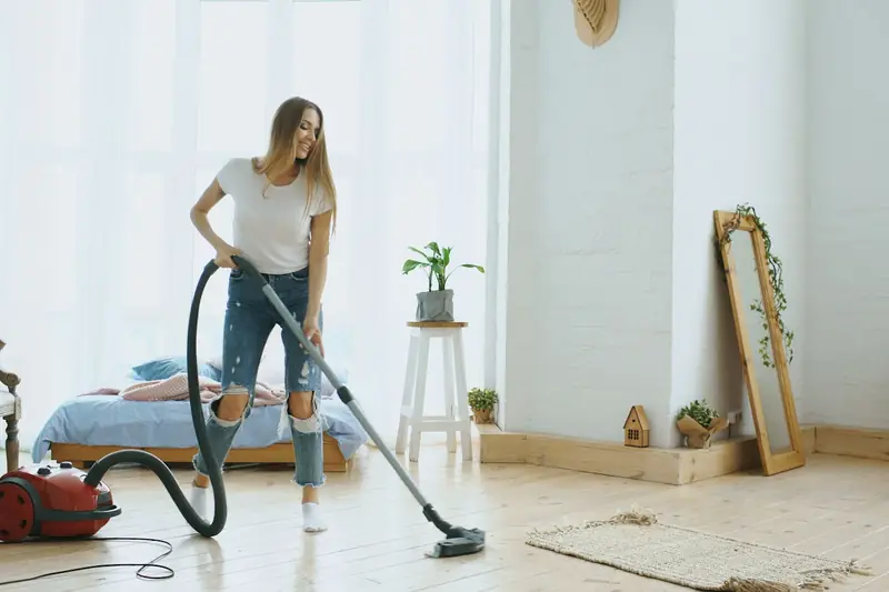 Persona pasando la aspiradora por el piso de un apartamento